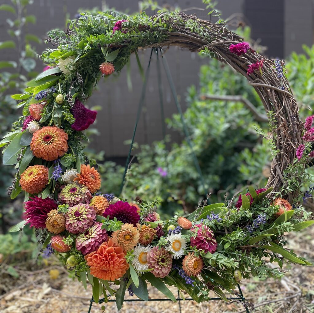 Natural grapevine wreath with wild foliage and summer flowers (zinnias, dahlias, strawflowers, celosia, lavender)